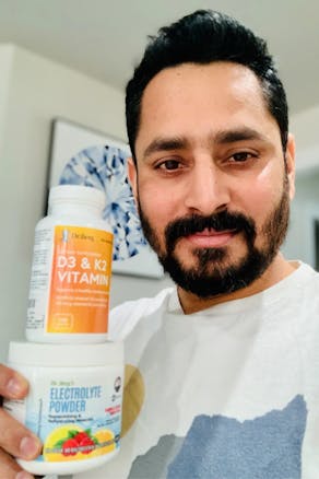 A man with Dr. Berg D3 & K2 Vitamin and Dr. Berg Electrolyte Powder products