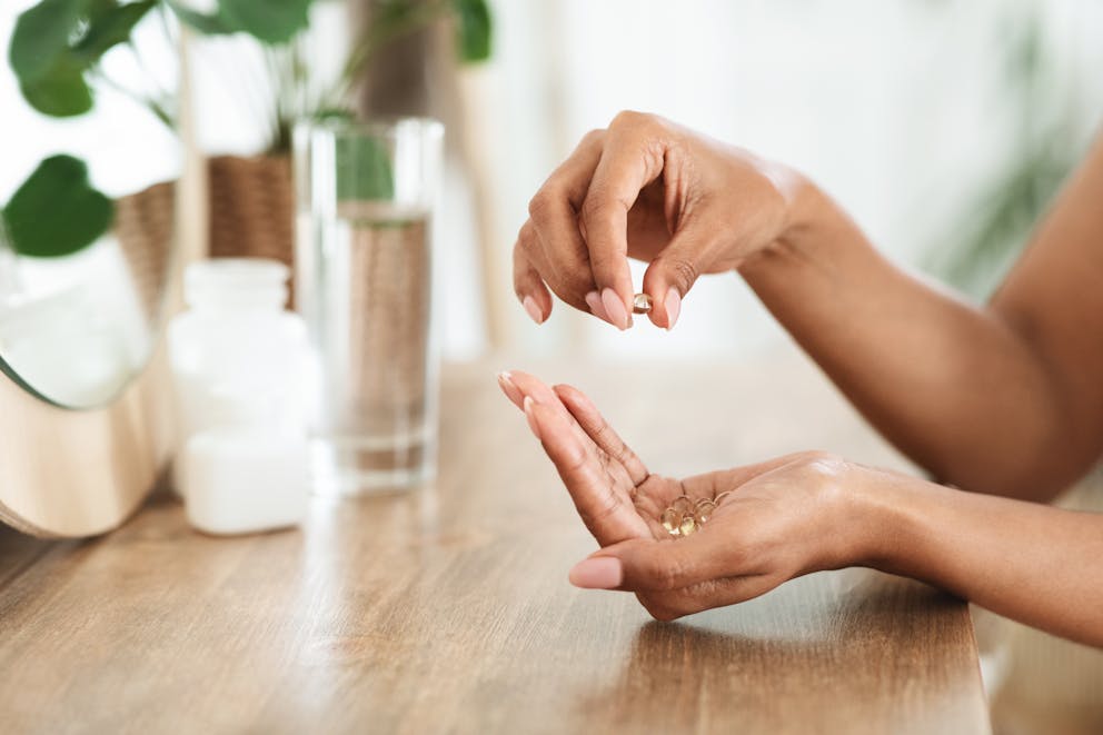 African Woman Taking Recommended Dosage of vitamin d and magnesium Capsules