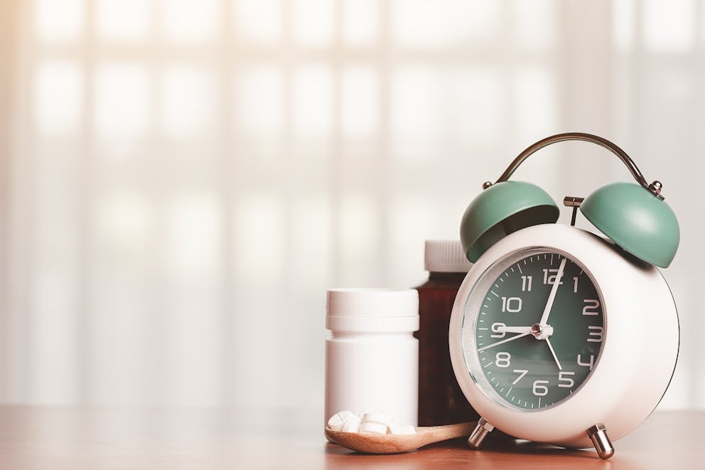 Alarm clock and supplements on a wooden spoon