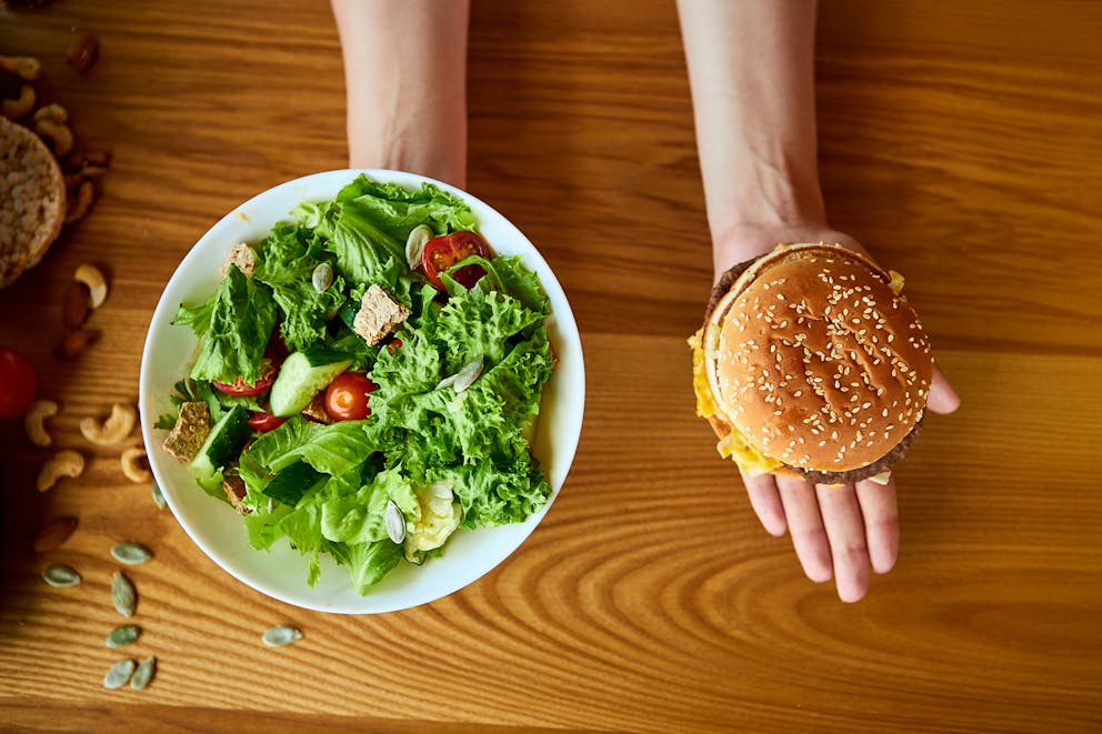 Woman holding salad and cheeseburger