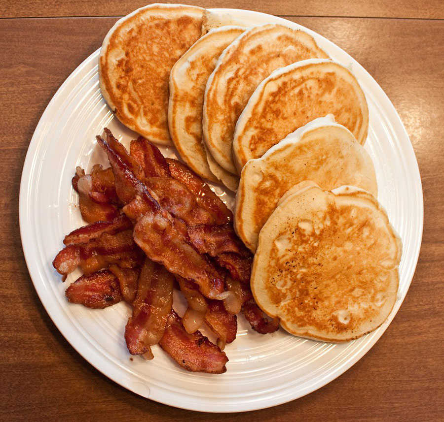 Grain-free pancakes piled on a plate with bacon on the side