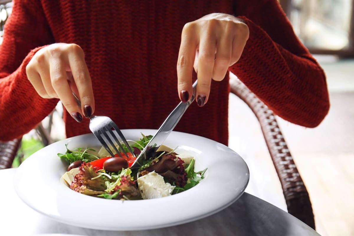 Woman eating tasty salad in cafe | Benefits of Only Eating One Meal A Day