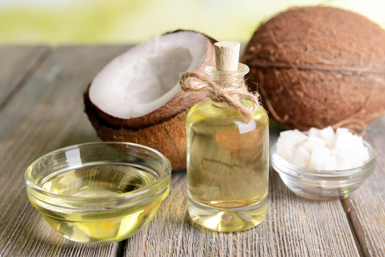 Coconuts on wood surface next to coconut oil | The Top 3 Reasons for Using Coconut Oil