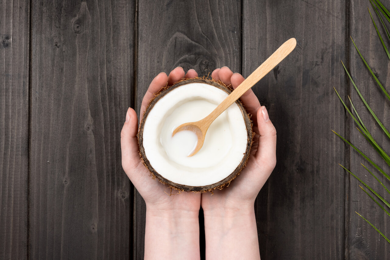 Person holding coconut and spoon | The Top 3 Reasons for Using Coconut Oil