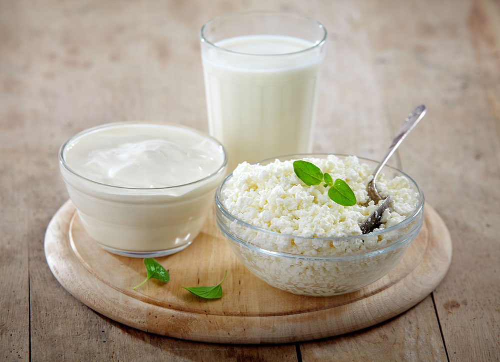 Dairy products on a wood table – milk, cheese, yogurt, butter, and cream cheese.