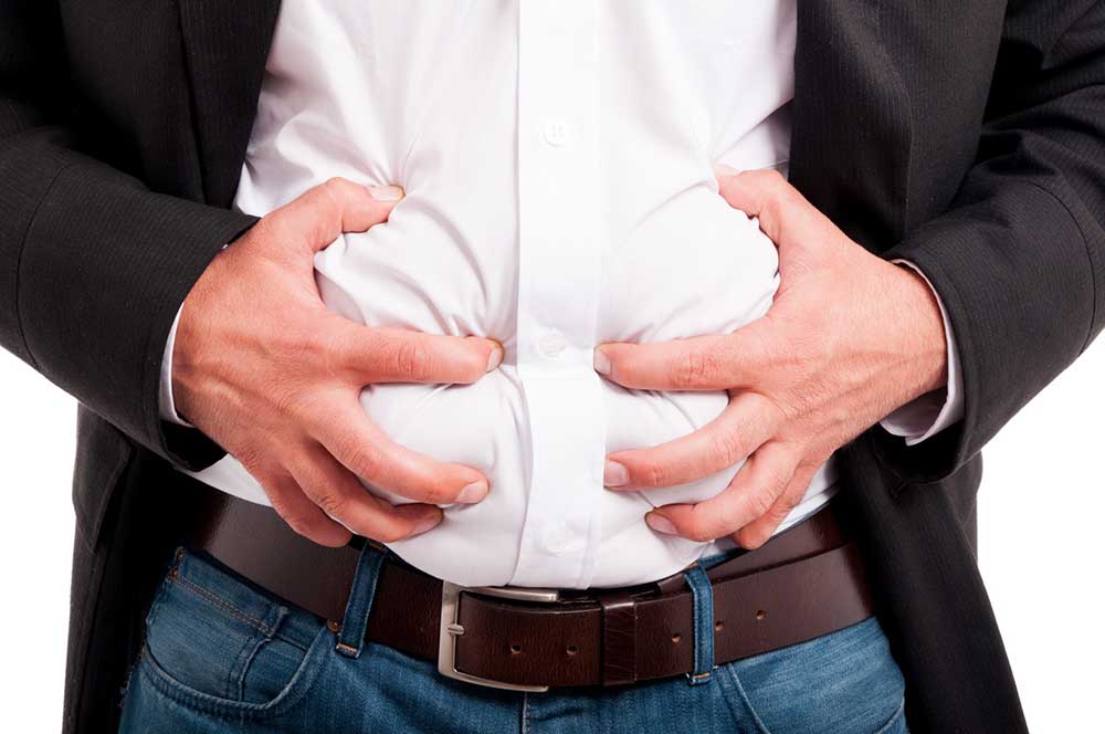 Man with bloated abdomen gripping his stomach in pain with his hands | 5 Healthy Habits for Bloating and Belly Fat