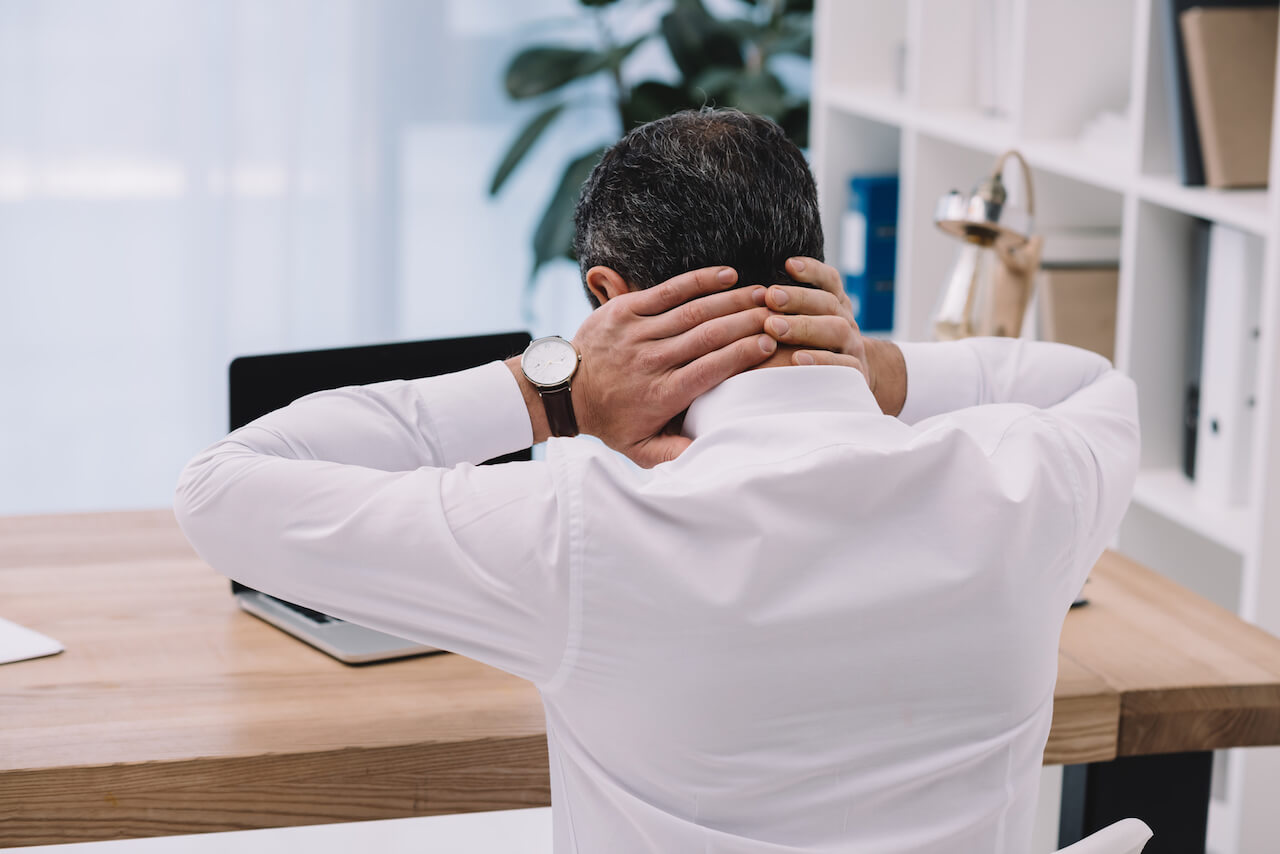Man with neck pain while sitting at a desk working. | 5 Tips in Dealing with Old Injuries as you are Aging