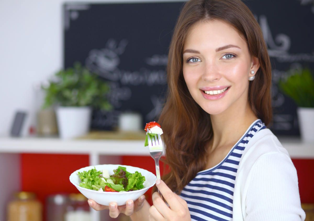 Young woman eating salad and holding a mixed salad | 5 Tricks to Make Intermittent Fasting Work Faster