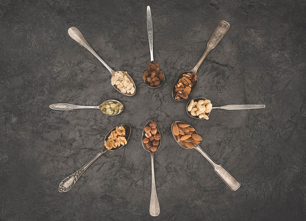 Assorted types of nuts held in silver spoons in a circle