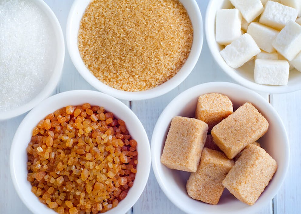 Variations of sugar in separate white bowls on a wooden surface. | 7 Things that Boost Fat Storing Hormone Sensitivity or Reverse Fat Storing Hormone Resistance