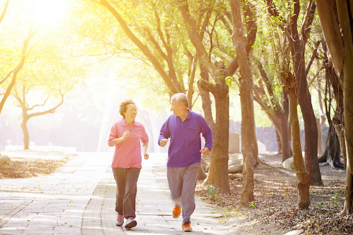 Older couple walking in a sunlit park. |  7 Tips to Lower Uric Acid