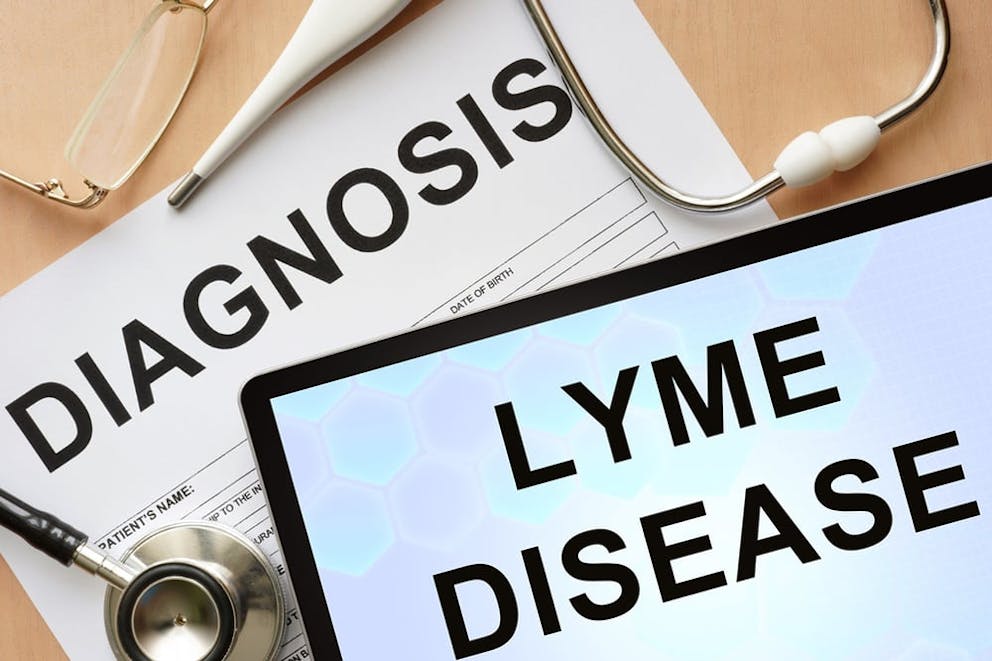 Tablet with Lyme Disease text, medical papers and equipment in background, Lyme disease diagnosis.