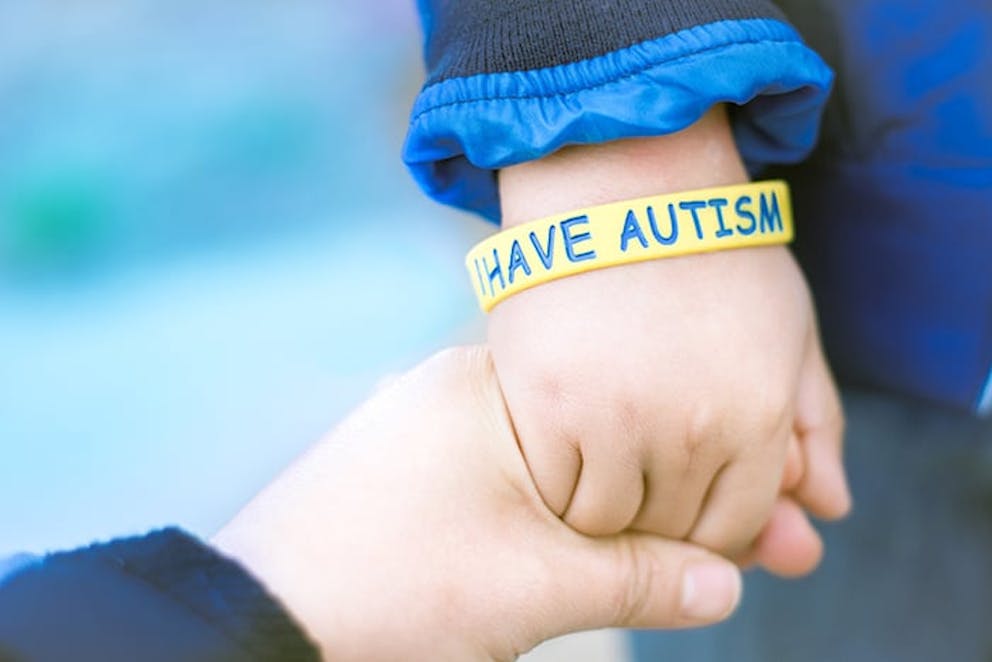 a photograph of a small child’s wrist with a bracelet saying I have autism