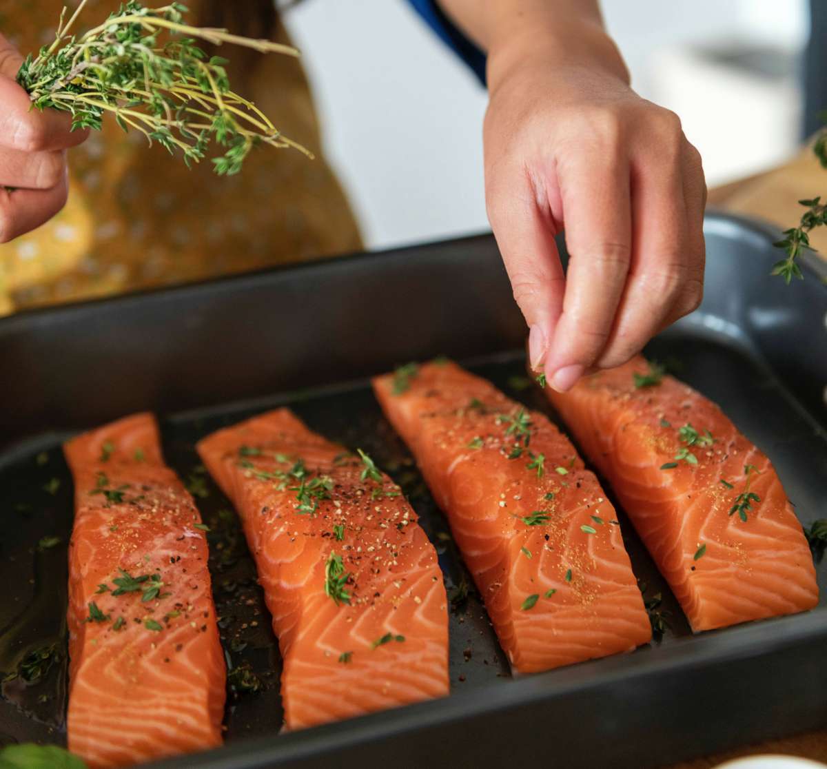 Woman putting seasonings on salmon | A Common Beginner Dieting Confusion