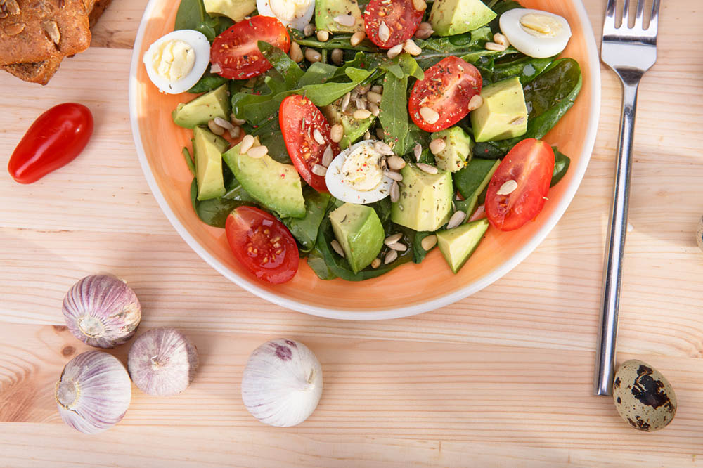 Salad garnished with healthy high-fat foods like avocados, eggs, and seeds.| 9 of the Best High-Fat Foods for Keto