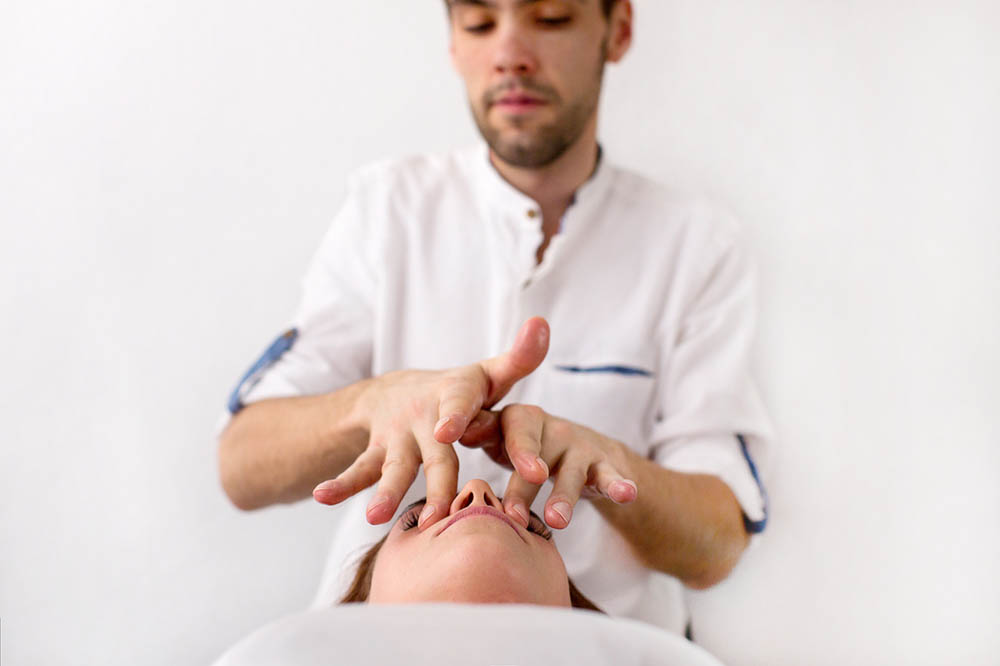 A man does acupressure with his fingers on a woman’s face near her nose | Acupressure for a Nose Injury