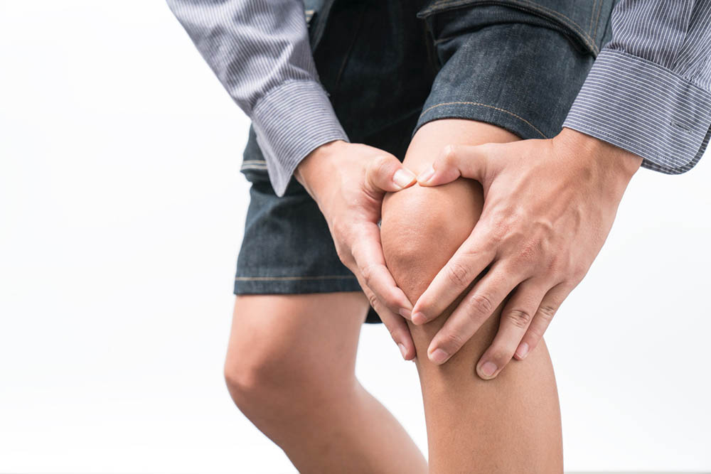 A man holds his hands on his knee to do acupressure for pain relief