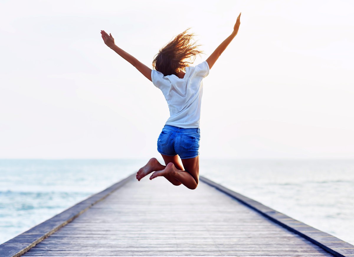 Back view of jumping girl on the pier | Amazing Health Benefits of Prolonged Fasting | prolonged fasting vs intermittent fasting