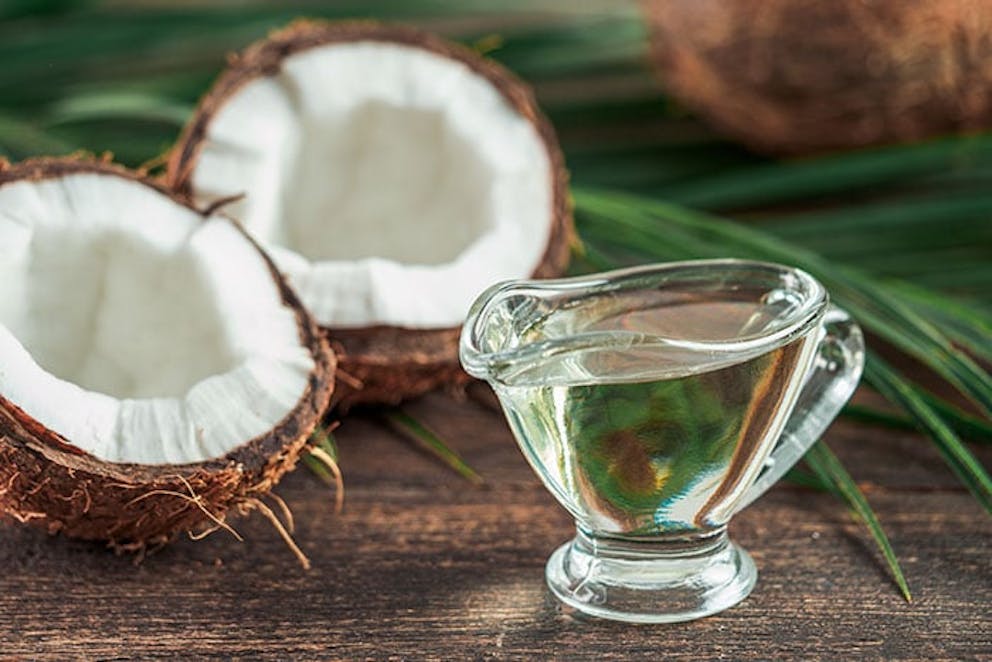 a small pitcher of MCT oil next to two coconut halves