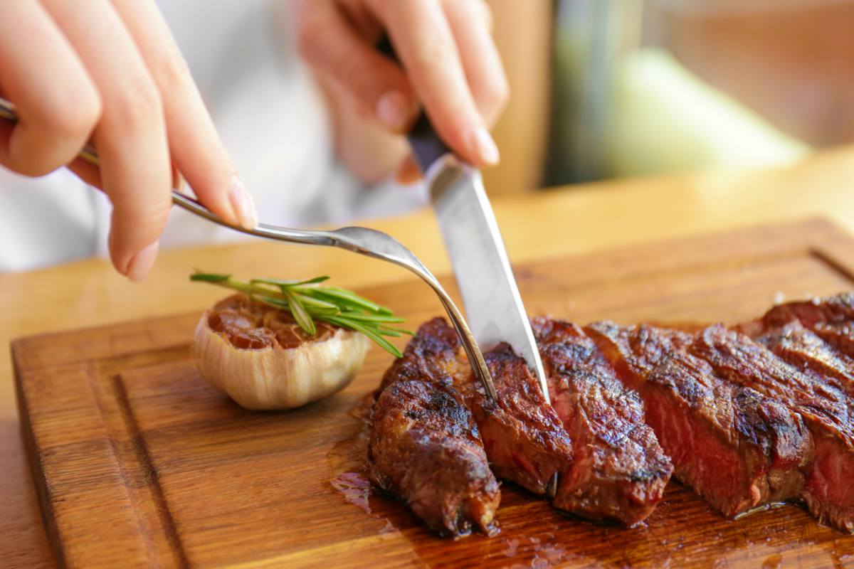 Young woman eating grilled steak in restaurant | An Overview Of The Atkins Diet