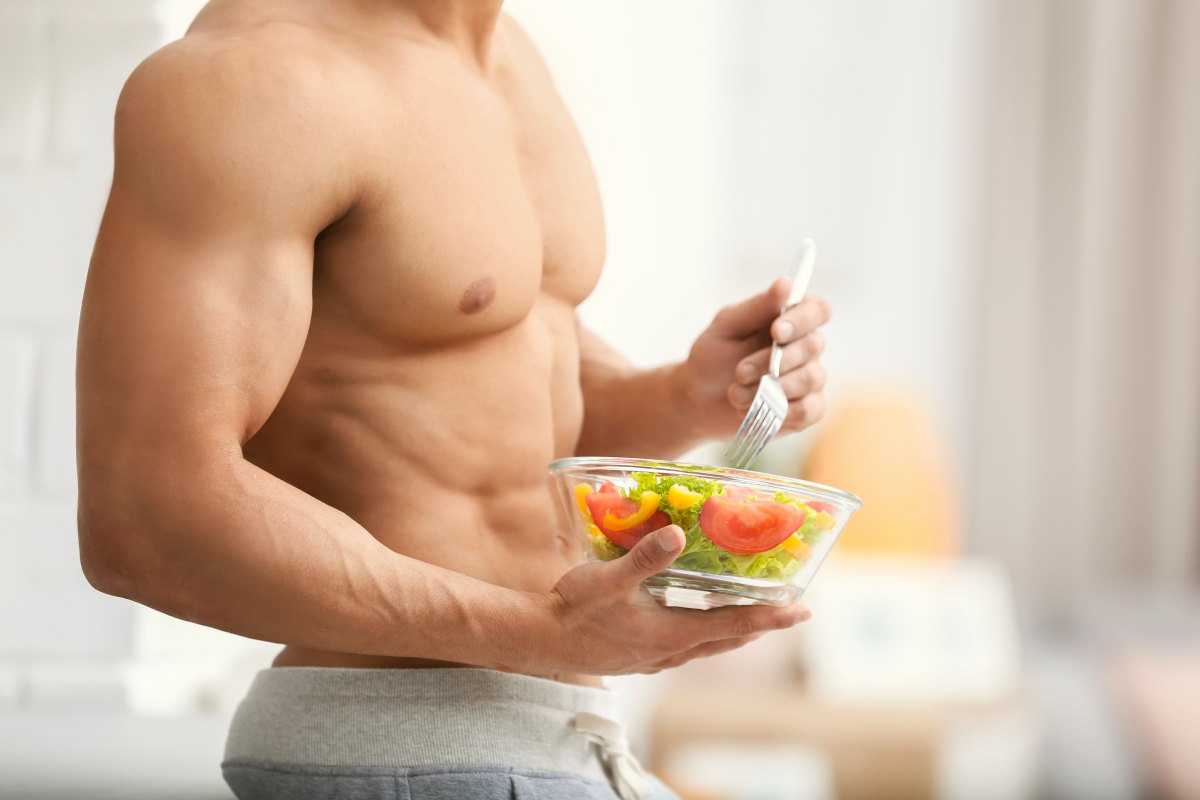 Handsome muscular young man eating salad in kitchen | An Overview Of The Atkins Diet