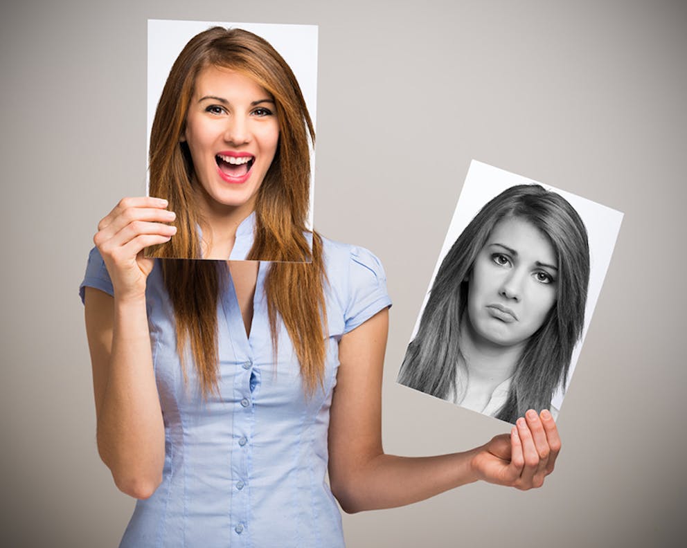 Improved mood concept, woman changing her mood and holding picture of smiling face and frown face.