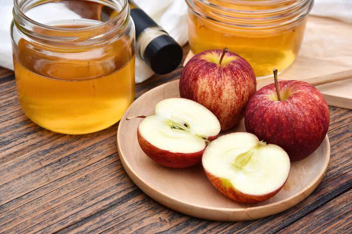 Apples on a wood table with apple cider vinegar | Best Asthma Remedies