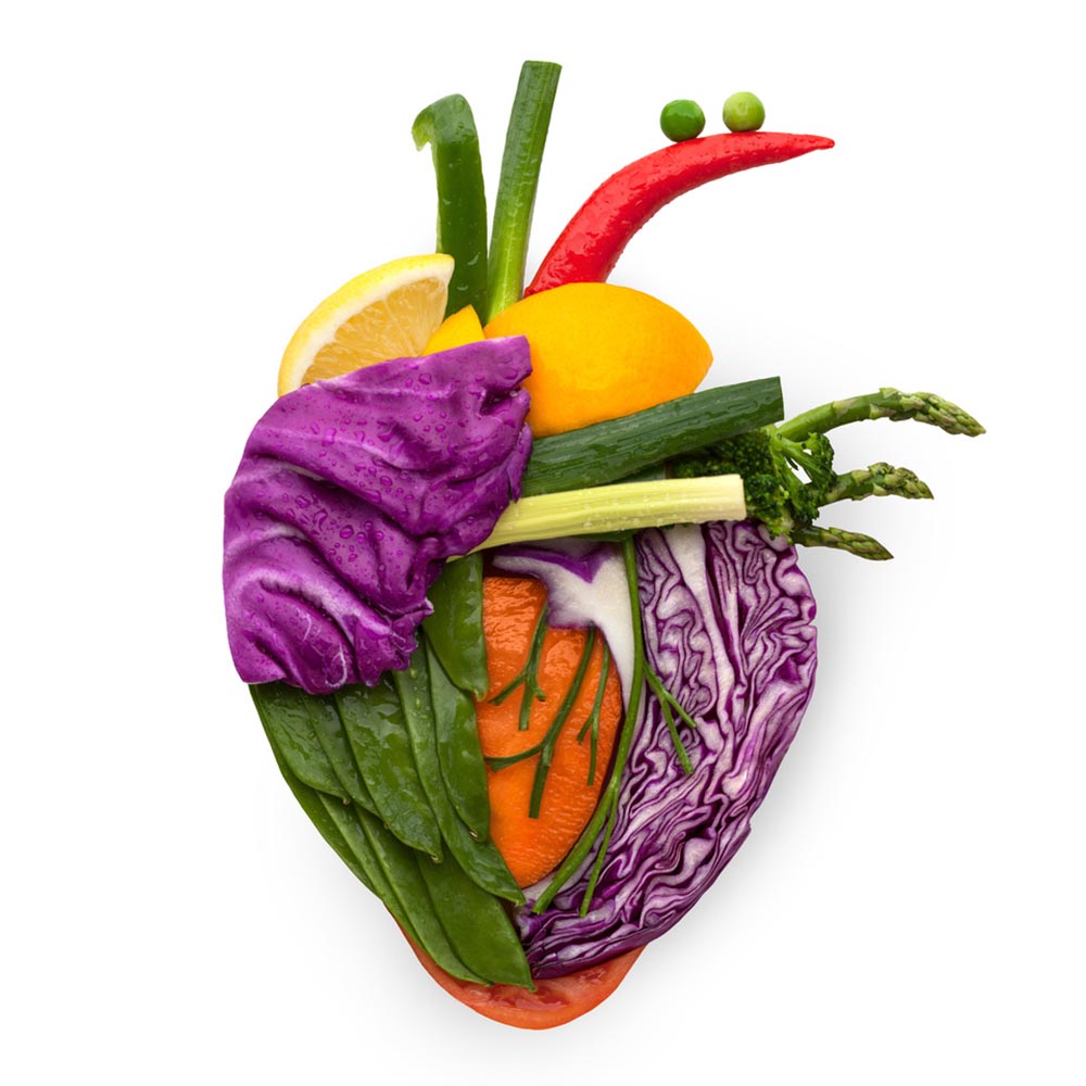 The shape of a human heart made out of healthy vegetables like cabbage, peas, and peppers