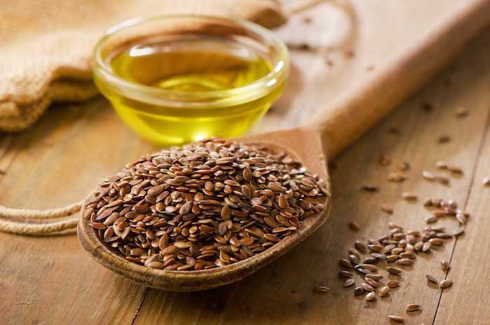 A spoon of flaxseed sitting next to flaxseed oil. |  Best Remedies for Dandruff
