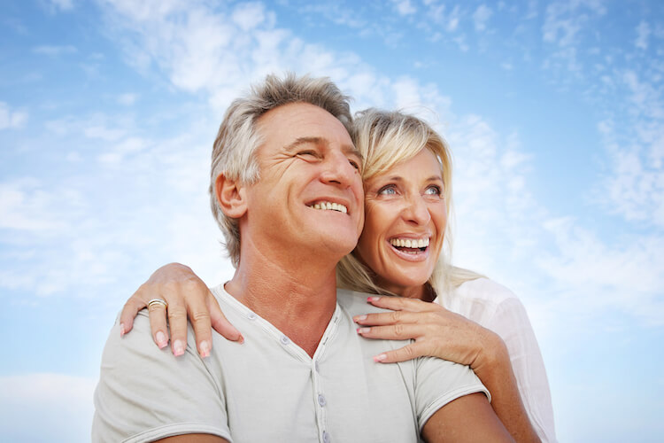 Happy smiling older couple with blue eyes against blue sky background