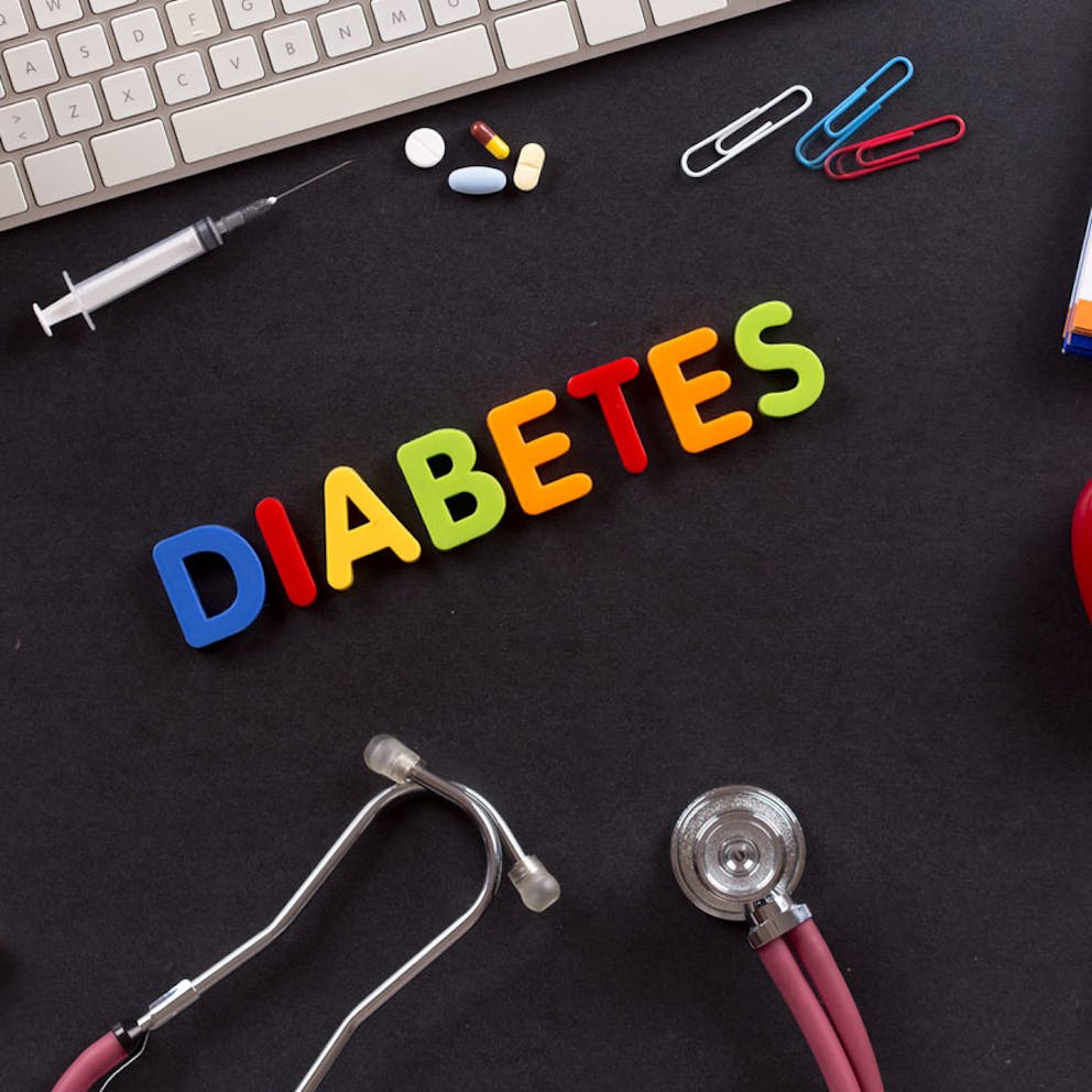Diabetes spelled in colorful letters on black background with medical supplies.