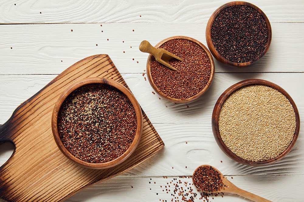 red, white, and black quinoa seeds in wooden bowls