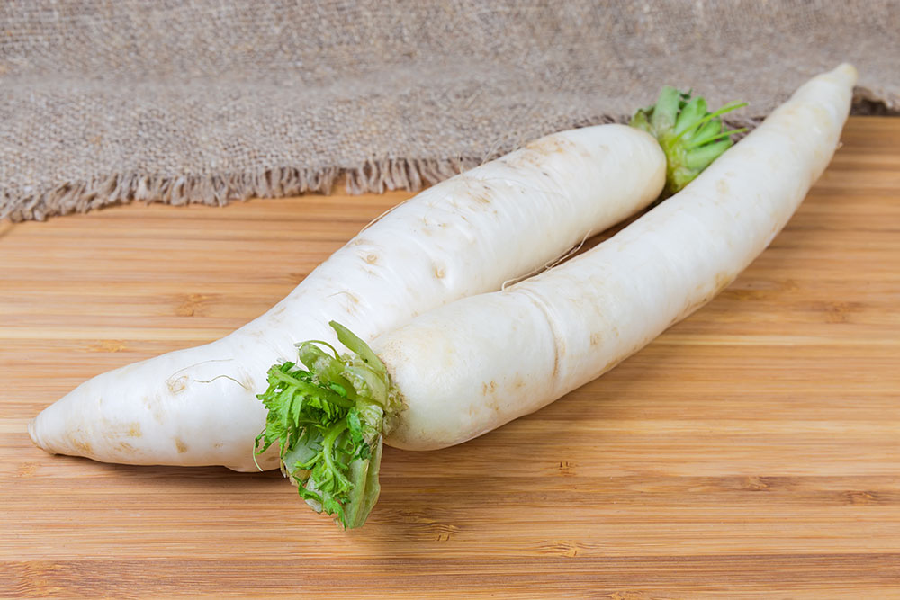 two daikon radishes on a wooden board