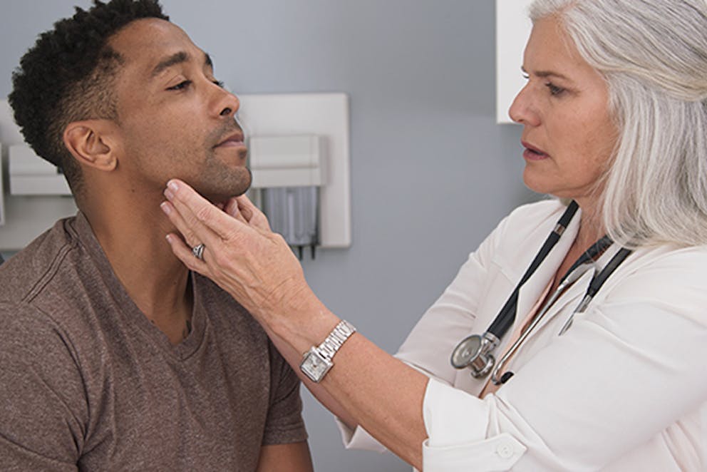 a photo of a woman medical professional checking a man’s lymph nodes