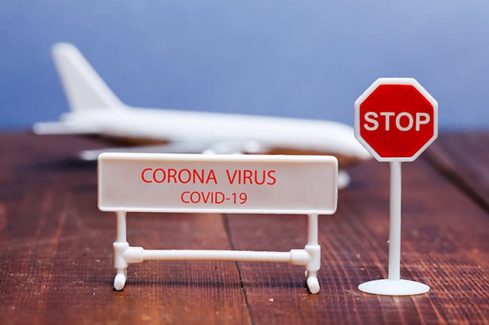 Coronavirus COVID-19 text on toy sign with stop sign, toy airplane in background. Stop coronavirus.