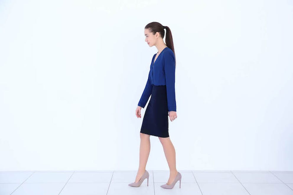 A businesswoman walking with hunched posture |  Correct Stretch for Hunchback
