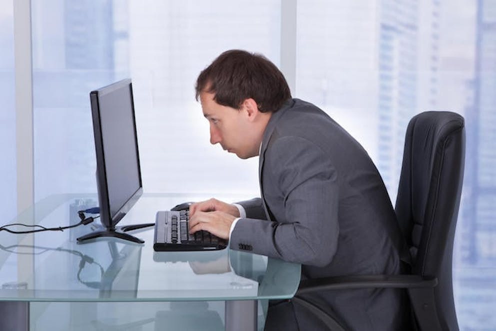 Man hunched over looking at a computer at work |  Correct Stretch for Hunchback