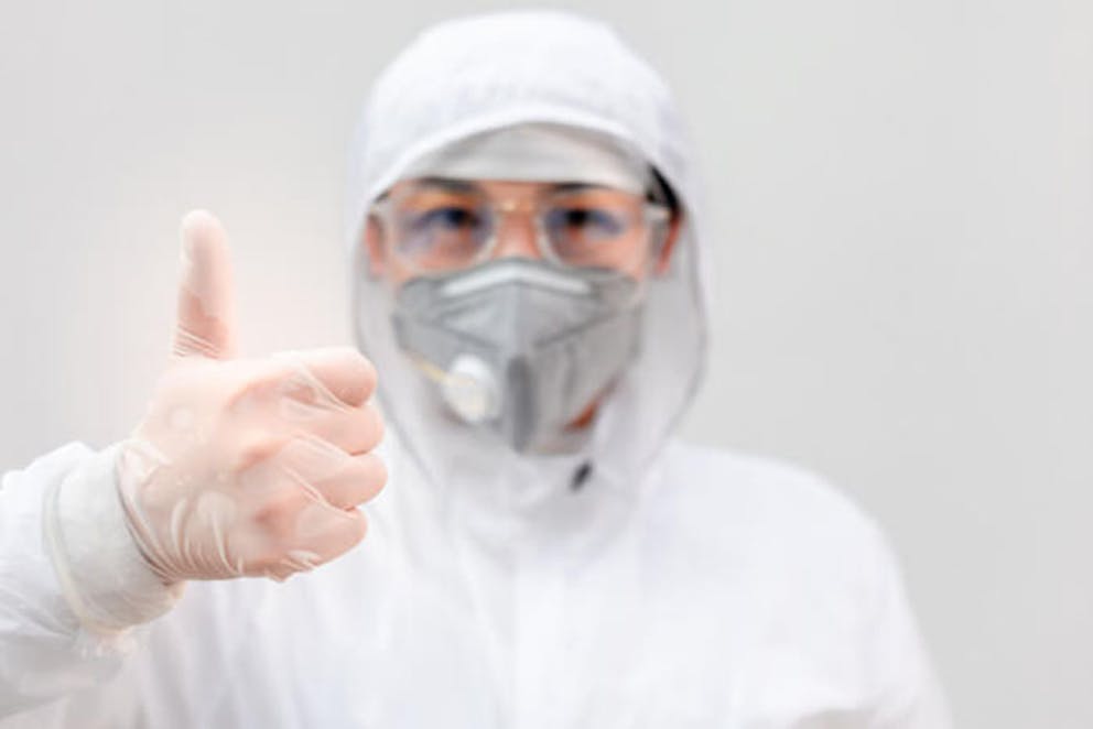 A medical doctor in protective gear giving a thumbs up 