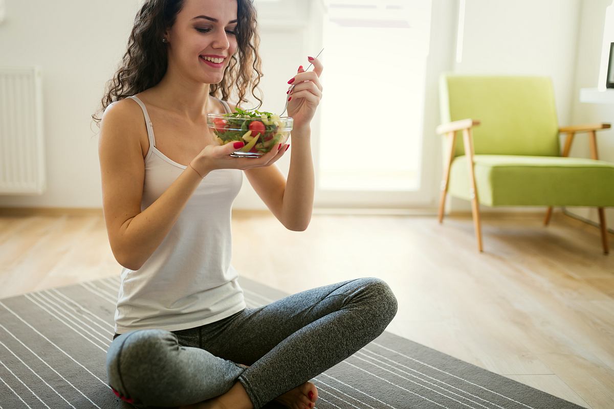 Woman eating healthy salad after working out at home | Cruciferous Can Help Thyroid Function Not Kill It