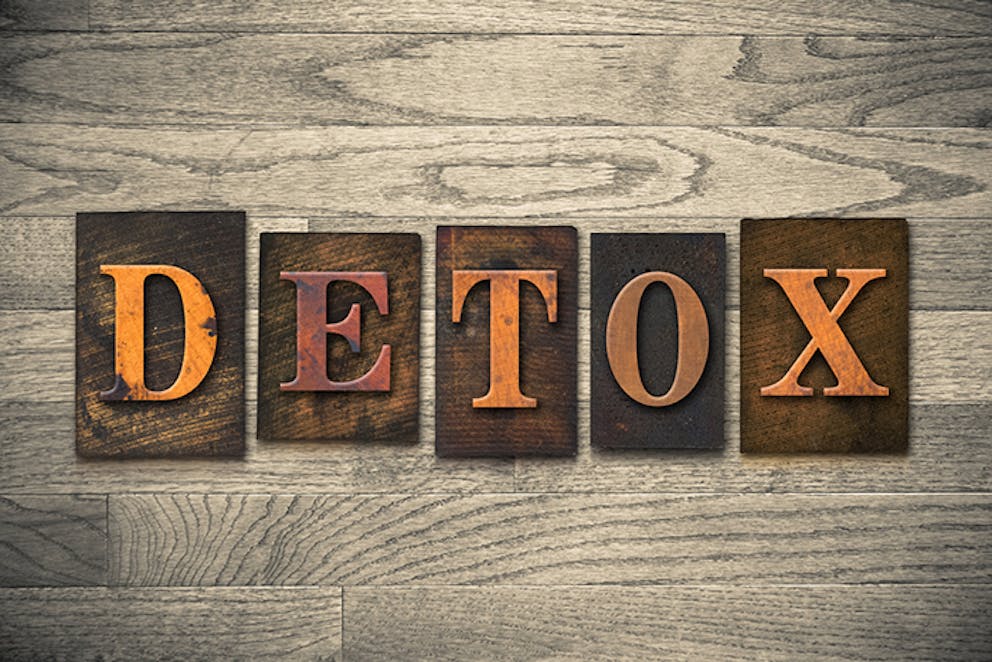 Word “Detox” written in vintage letters on wood background.