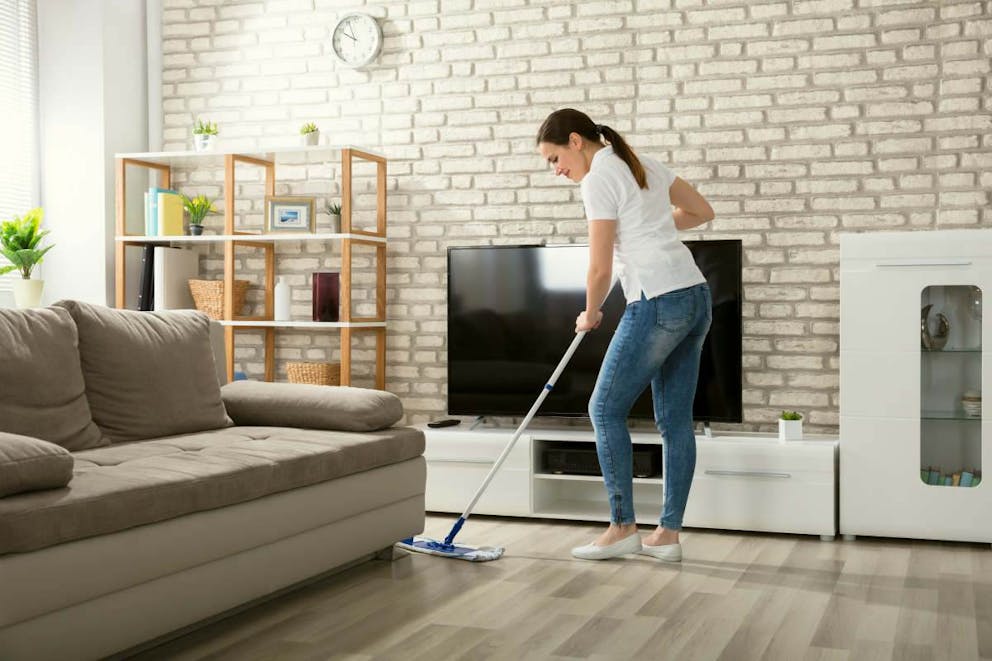 Happy Young Woman Cleaning The Hardwood Floor With Mop In Living Room | How To Stop Snacking Out Of Boredom | snacking out of boredom
