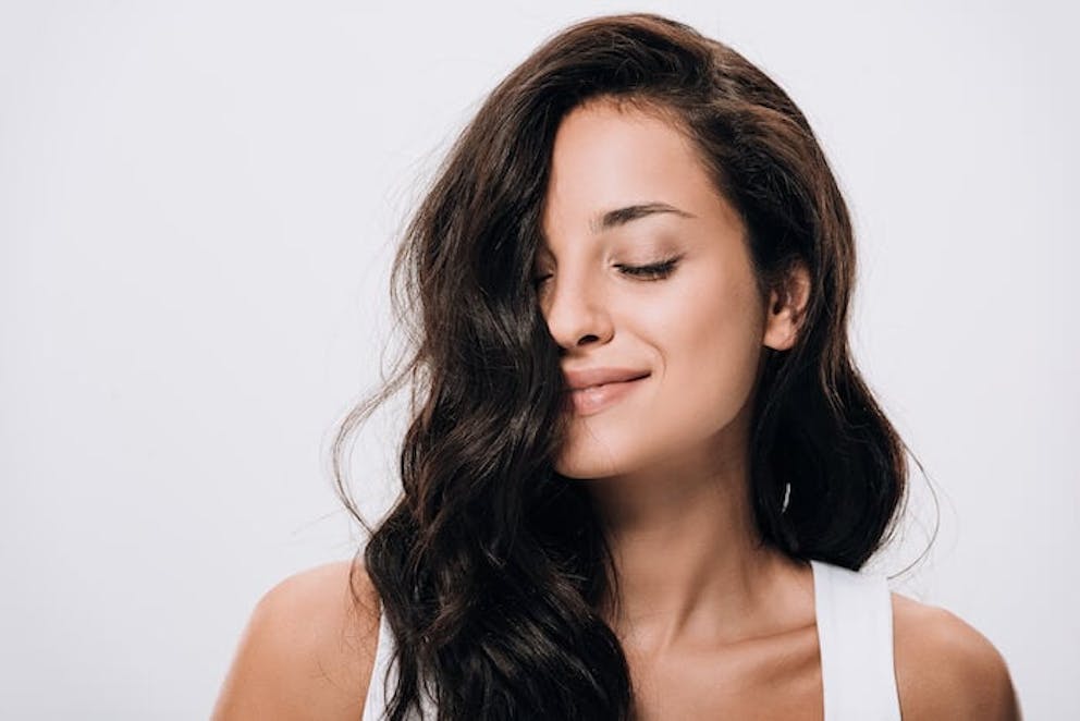 A happy woman smiling and showing off her beautiful, healthy hair | Eat Avocados and Eggs for Amazing Hair and Nails