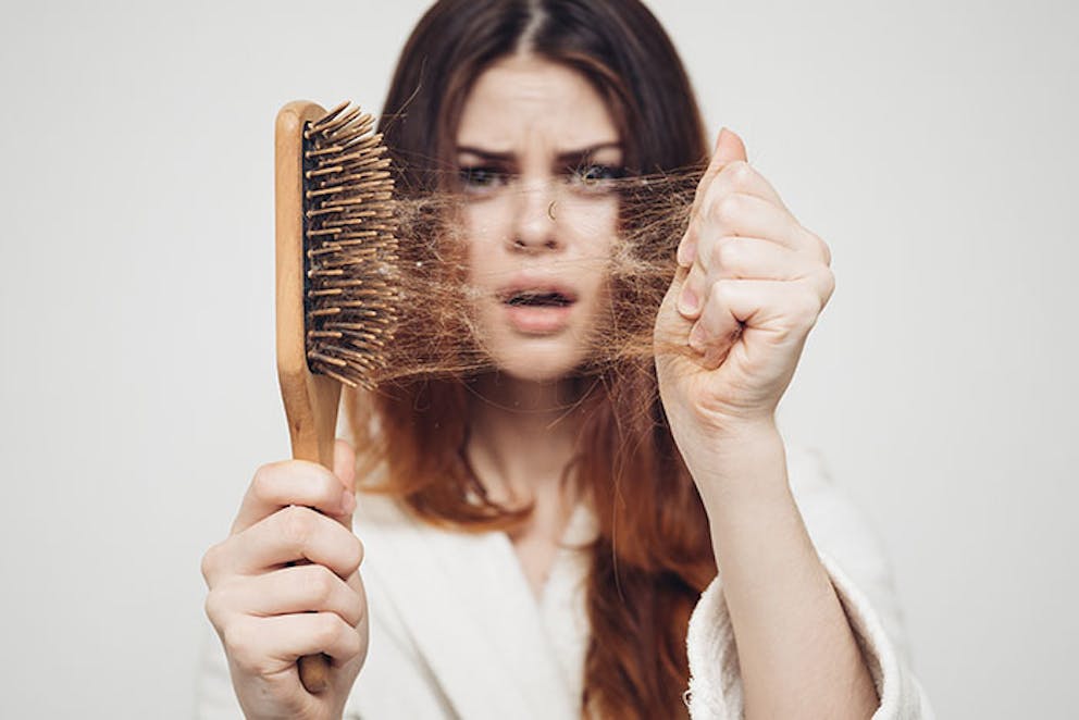 a young woman who’s hair is coming out in clumps into her brush