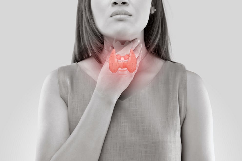 woman with hypothyroid symptoms holding neck in black and white | Hashimotos and Ketosis