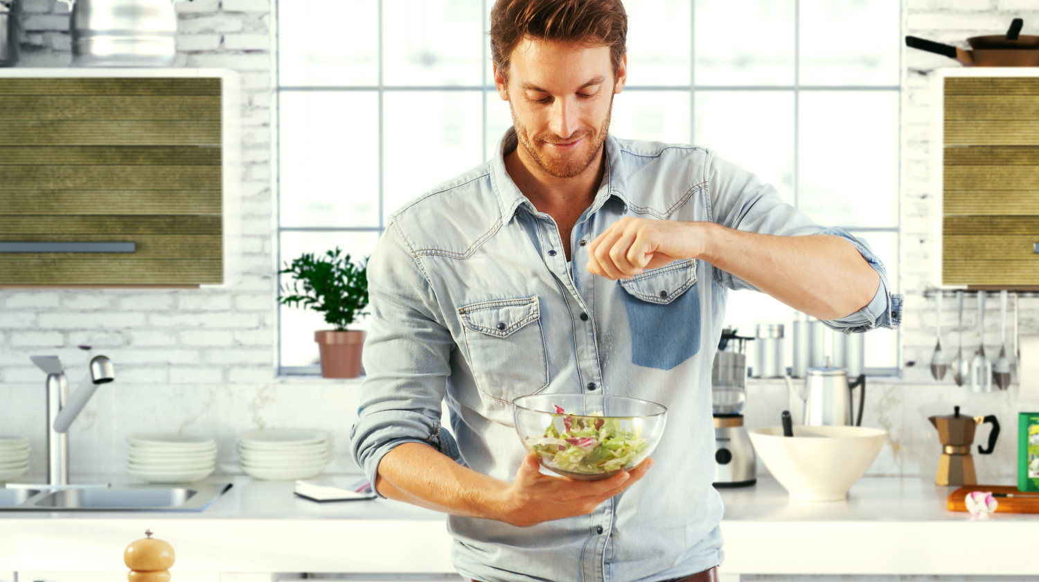 Featured | Handsome man cooking at home preparing salad in kitchen | Can I Use Herbs and Tubers When I’m On A Ketogenic Diet?