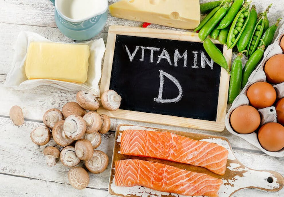 A sign with “vitamin D” written on it surrounded by foods high in vitamin D | High Doses of Vitamin D Can Deplete Magnesium