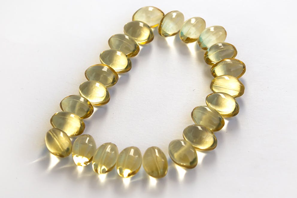 Vitamin D supplement capsules lined up in shape of the letter D.