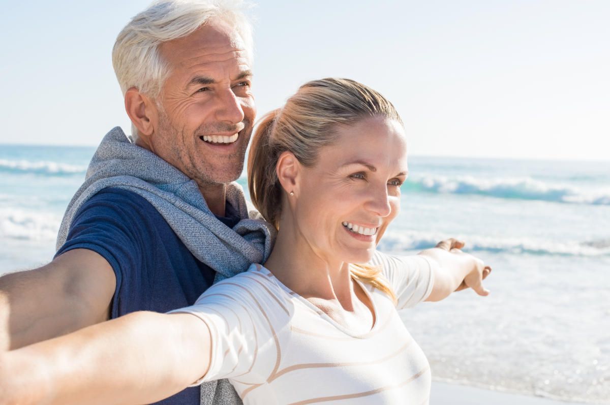 Happy senior couple standing on beach with arms outstretched | How To Get Rid Of Wrinkles and Reverse Them Effectively