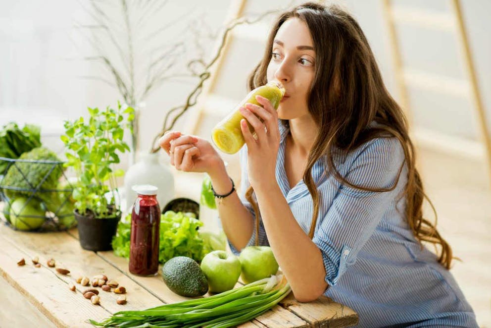 Beautiful woman sitting with healthy green food and drinking smoothie at home | How To Fix A Sore Throat Within 2 Minutes! WITHOUT Pills, Herbs Or Drugs | persistent sore throat | what to eat when you have a sore throat