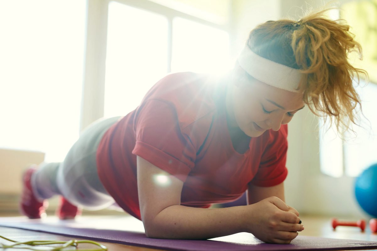 Portrait of young obese woman working out on yoga mat in fitness studio | How To Get Rid Of Belly Fat With Keto And IF